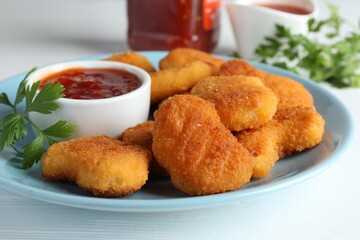 Tasty chicken nuggets with chili sauce and parsley on white table, closeup