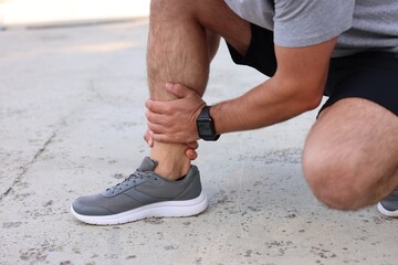 Man suffering from foot pain outdoors, closeup
