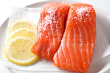 Pieces of fresh salmon with salt and lemon on white table, closeup