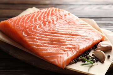 Piece of fresh salmon and spices on wooden table, closeup