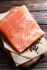 Piece of fresh salmon and spices on wooden table, closeup
