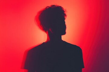 Anonymous Male Silhouette in Black T-Shirt Against Vibrant Red Gradient Background - Abstract Concept of Identity and Anonymity
