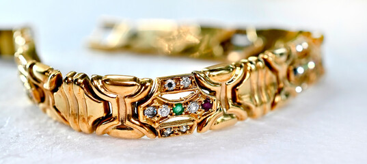 A gold bracelet with a couple of precious gems set within a section of the bracelet. close up