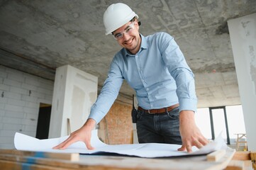 Portrait of an architect builder studying layout plan of the rooms, civil engineer working with...