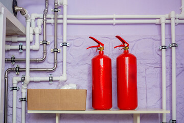 Pipes from boiler equipment. Two fire extinguishers near wall. Pipeline for heating system. Many...