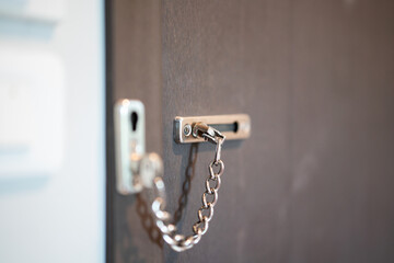 A chain lock on the wooden bedroom's door, that using for security. Building interior object,...