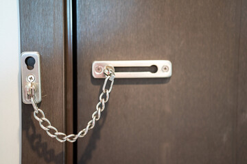 A chain lock on the wooden bedroom's door, that using for security. Building interior object, close-up.