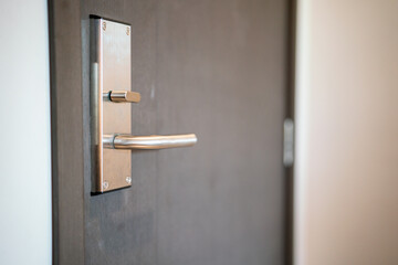Luxury chrome steel handle of wooden door. Interior object, close-up and selective focus.