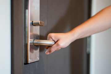 Action of a human hand is holding on standless door lever handle to open the wooden door. close-up...