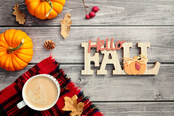 Hello Fall concept. Autumn flat lay composition with pumpkins, coffee cup, warm plaid on wooden desk table.