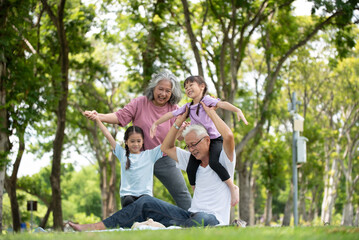 Happy Asian family children having fun and playing with her grandparents in the park