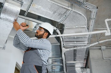 An Indian worker inspects the ventilation system in an office building