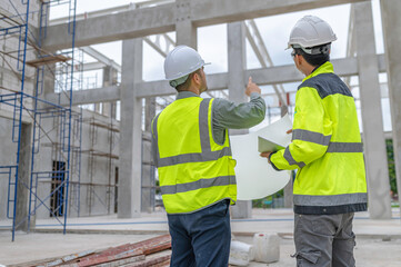 Two Asian engineer working at site of a large building project,Work overtime at construction site,Team of engineer discus at site,The architect, supervisor, and foreman meet to discuss the design