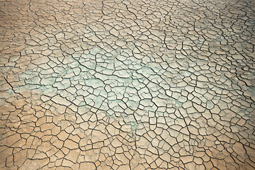 Overhead image of a desert basin with a patchwork of mineral deposits and dry cracked mud.