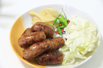 Several sausages on a plate with vegetables as a side dish.