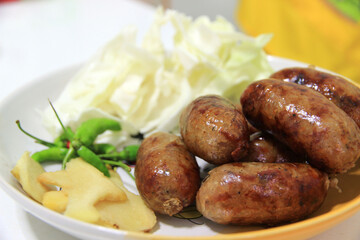 Several sausages on a plate with vegetables as a side dish.