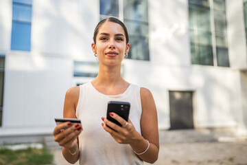 Young woman stand outdoor and buy online on cellphone with credit card