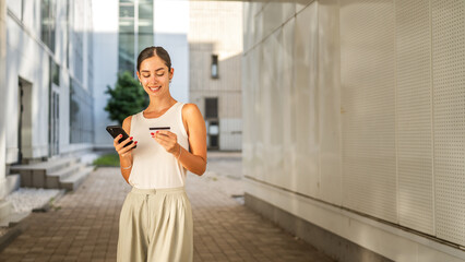 Young woman stand outdoor and buy online on cellphone with credit card