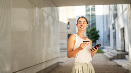 Young woman stand outdoor and buy online on cellphone with credit card