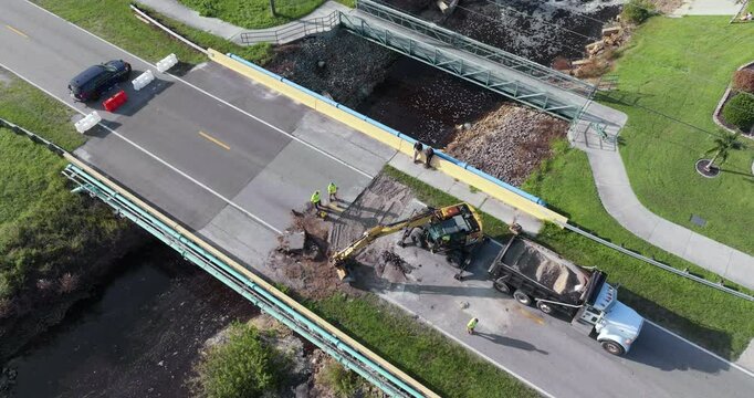 Road construction. Workers repairing destroyed bridge after hurricane flooding water washed away asphalt in Florida. Construction equipment at roadwork site