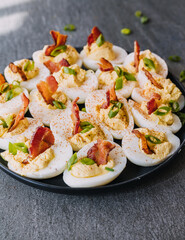 Deviled eggs garnished with bacon, green onion and smoked paprika