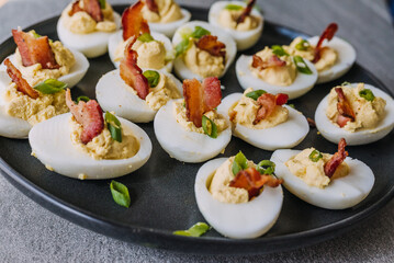 Deviled eggs garnished with bacon and green onion