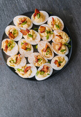 Deviled eggs garnished with bacon, green onion and smoked paprika