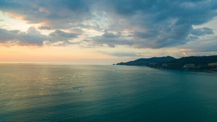 A breathtaking aerial view of a coastal bay at sunset, with golden light reflecting on the calm sea...