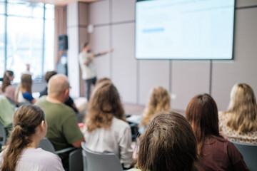 Blurry image of business presentation with audience seated in modern conference room, focusing on learning and collaboration