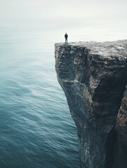 A solitary figure standing on the edge of a rocky cliff, overlooking a serene ocean under a misty sky.
