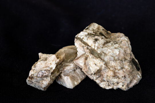 Samples from a granitic pegmatite consisting predominantly of plagioclase feldspar and biotite against a black background.