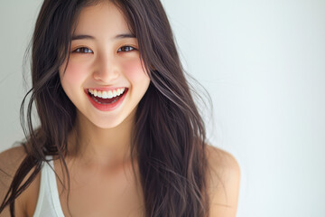 Naklejka premium A young Asian woman with long dark hair is wearing a white tank top. She is smiling with her mouth open wide.