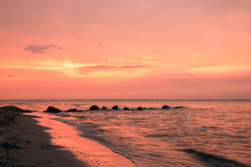 Romantic seascape with beach scene and bright red sky sunset.