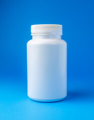 White medical plastic jar against blue backdrop. Packaging for drugs, vitamins. Pill container.