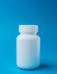 White medical plastic jar against blue backdrop. Packaging for drugs, vitamins. Pill container.