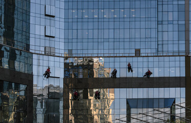 the glass wall of the building with workers who wash the windows