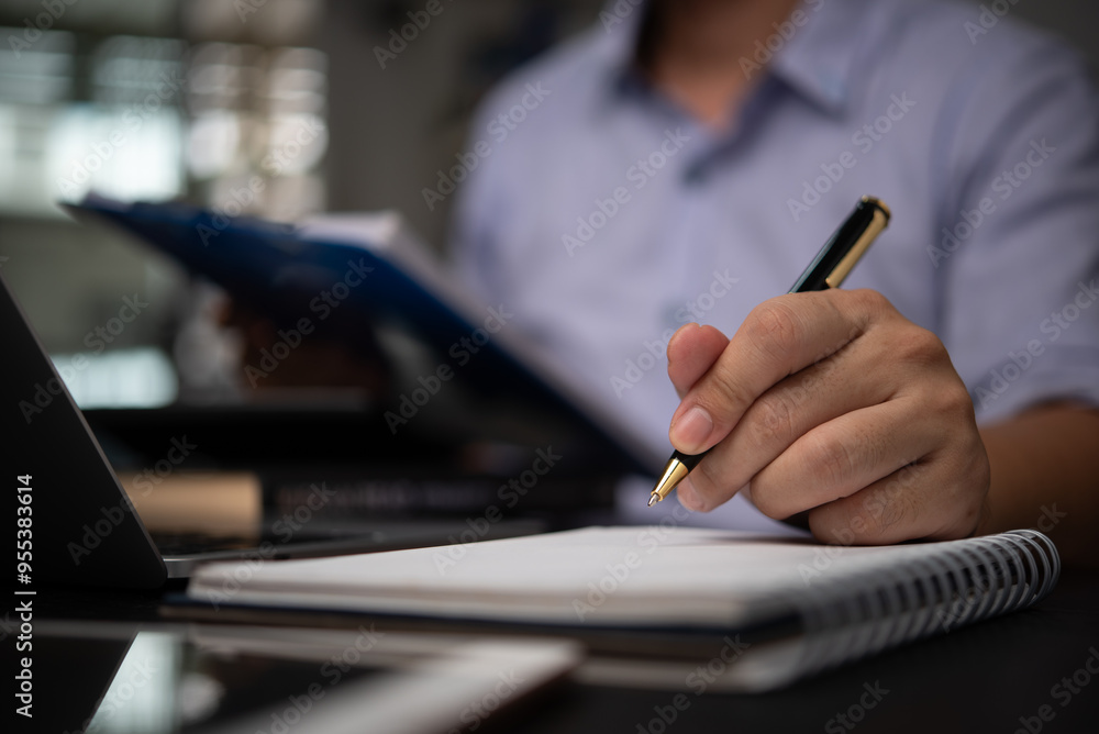 Aufkleber business professional taking notes in a notebook while reviewing documents at a desk planning organi