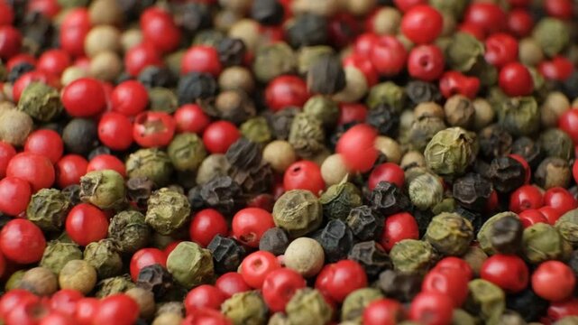 A mix of different types of peppercorns pouring, macro slow motion