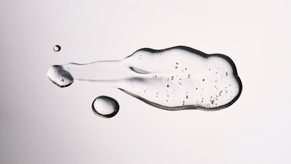 A smear of cosmetic gel close-up on a gray background. Appetizing texture with bubbles.