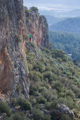 A tightrope walker walks along a cable stretched over a canyon.