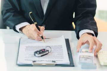 Car salesman signs car sales contract with cash and hands over keys to customer. Automotive business concept.