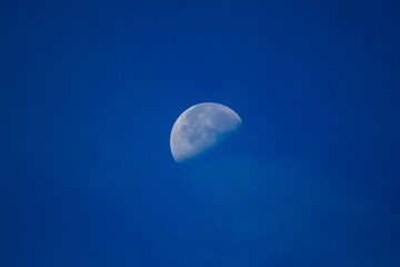 Photo of the moon in the blue sky.