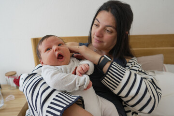 Mother lovingly holds newborn baby in her arms, with the baby looking curiously around, capturing a tender family moment, perfect for themes of parenting and early childhood