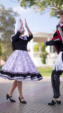 pareja de huasos bailando cueca chilena en la plaza de la ciudad
