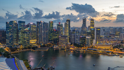 Aerial view of Singapore business district skyscrapers at evening with water reflections day to night timelapse