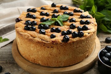 Delicious homemade blueberry pie with mint and fresh berries on wooden table, closeup