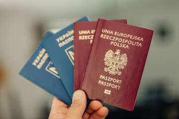 man hand holds both Ukrainian and Polish passports, symbolizing migration and citizenship