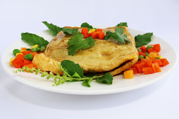 A thick omelet decorated with basil flowers and leaves, carrots, peas, and corn. In a cream-colored porcelain dish white background

