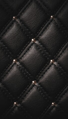 Obraz premium A close-up of a textured black genuine leather surface with a diamond stitch pattern and small golden studs, an elegant dark, luxury, sexy background