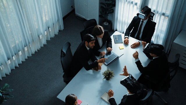 Top view of manager working on laptop and sending data analysis to business people by using VR glass headset while diverse team moving gesture while working together to planning idea. Directorate.